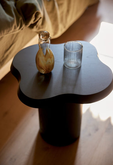 relación entre material y forma de mesa auxiliar redonda de madera lacada negra de Gabrielle Paris