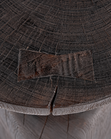 Mesa auxiliar redonda de madera oscura, detalle de las vetas y grietas del tablero