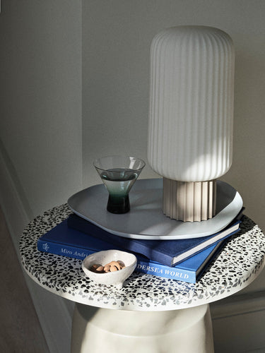 Mesa auxiliar de terrazo en una composición con textiles oscuros