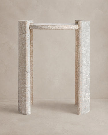 Mesa auxiliar Vical de travertino beige sobre pared y suelo topo claro texturizado