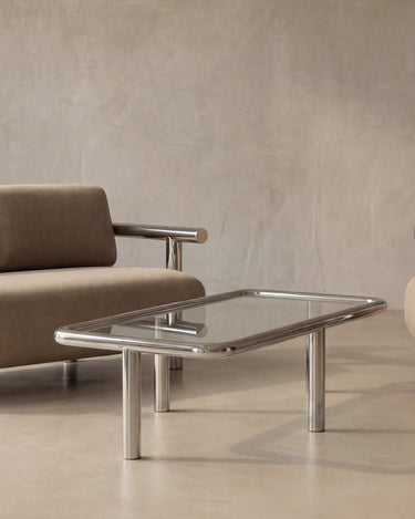 Mesa de centro de acero inoxidable y cristal ahumado de Gabrielle Paris junto a un sofá