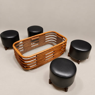 Mesa de bambú curvado mostrada en una composición con cuatro taburetes negros.