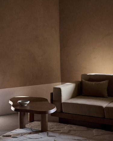 Mesa de centro con acabado teca de Gabrielle Paris junto a un sofá beige
