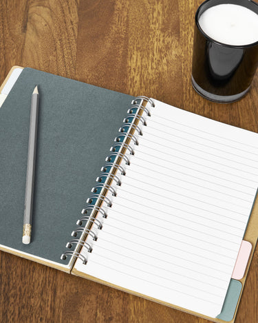 Cuaderno, lápiz y vela sobre la superficie de nogal.
