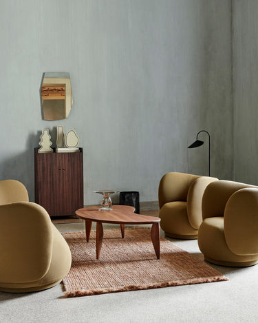 Mesa de Ferm Living: mesa entre sillones mostaza y un armario bajo acanalado.