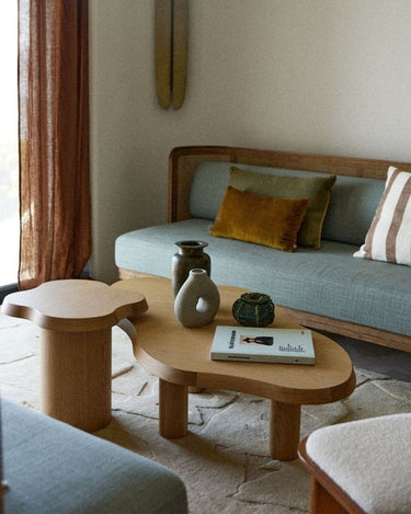 Mesa de centro de roble natural junto a un sofá azul y una mesa auxiliar