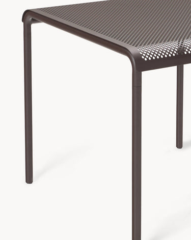 Detalle del canto perforado y unión con pata tubular marrón.