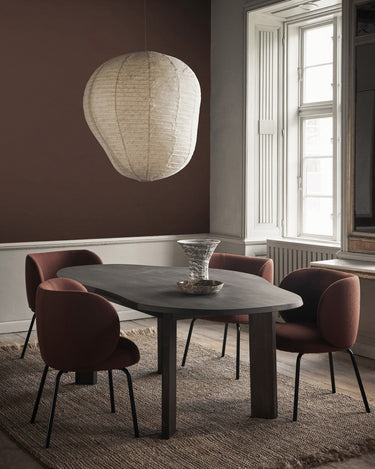 Mesa de comedor orgánica de haya maciza de Ferm Living, haya oscura: mesa oscura en comedor con sillas tapizadas, lámpara de papel y jarrón.
