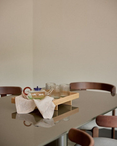 Mesa de comedor Gabrielle Paris: detalle del tablero caqui con una bandeja y vasos