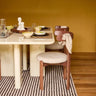 Mesa de comedor rectangular lacada en crema de Gabrielle Paris ante una pared ocre