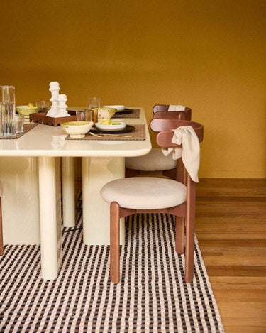 Mesa de comedor rectangular lacada en crema de Gabrielle Paris ante una pared ocre