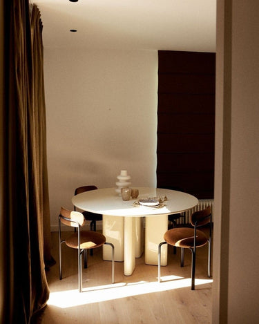 Mesa de comedor redonda lacada en crema de Gabrielle Paris junto a una ventana