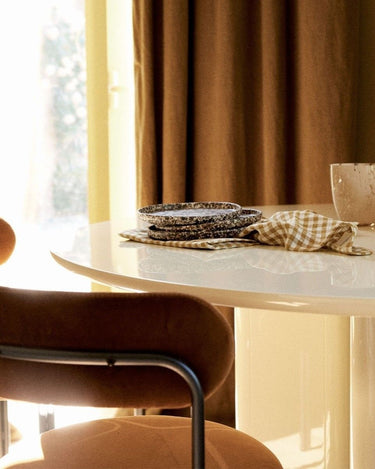 Mesa de comedor Gabrielle Paris: detalle del tablero crema con vajilla