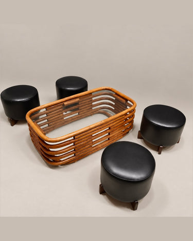 Mesa de bambú curvado mostrada en una composición con cuatro taburetes negros.