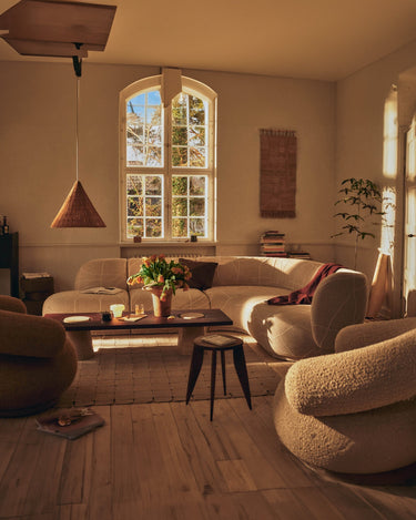 Mesa de centro de Ferm Living delante de un sofá y sillones en un salón.