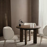 Mesa de comedor orgánica de haya oscura de Ferm Living en un comedor con sillas claras.