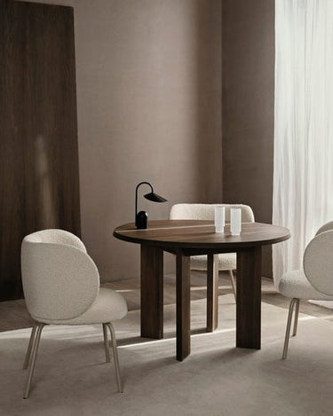 Mesa de comedor orgánica de haya oscura de Ferm Living en un comedor con sillas claras.