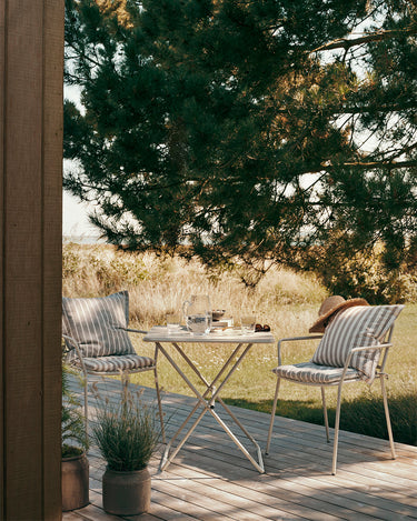Mesa de jardín beige gris bajo un árbol con sillas a juego
