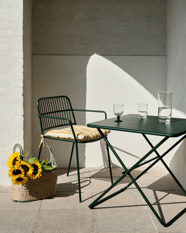 Mesa verde bosque con sillas negras en una terraza soleada