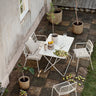 Mesa de jardín rectangular beige gris de Broste Copenhagen con cuatro sillas en un patio