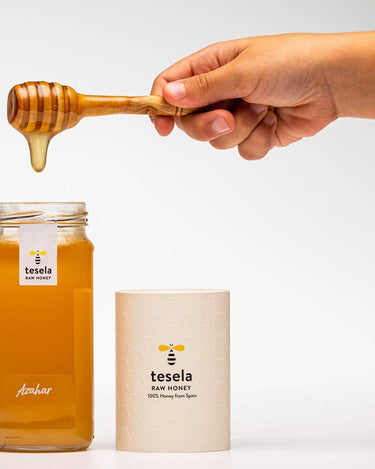 Mieles de azahar Tesela: tarro abierto junto al estuche y una cuchara de madera