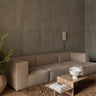 Módulo central profundo de sofá de lino natural de Ferm Living: ambiente con composición de varios módulos claros, mesa pétrea y pared gris.