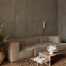 Módulo de sofá profundo de lino con brazo derecho de Ferm Living: ambiente de composición modular clara con mesa pétrea, jarrón blanco y pared gris; varios módulos juntos.