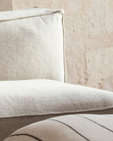 Detalle de asiento y respaldo de uno de los módulos Catena de lino natural junto a pared texturada.
