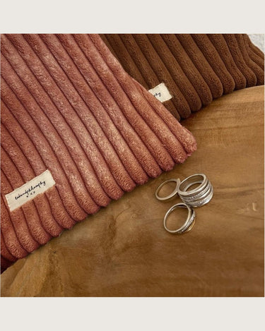 Neceser de maquillaje de pana color canela, junto a accesorios sobre una mesa