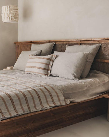 Pantalla de algodón y lana con relieve blanco roto, como suspensión junto a una cama con cojines