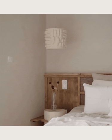 Pantalla de algodón y lana con relieve blanco roto, suspensión junto a un cabecero de madera