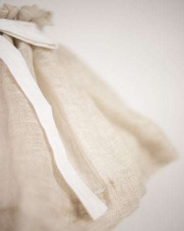Detalle del lazo blanco sobre el lino natural fruncido