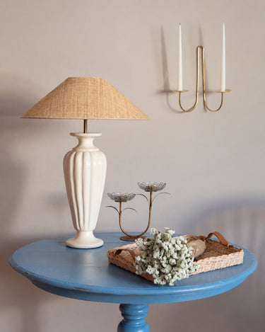 Pantalla de lámpara de Mahe Homeware en una composición con candelabros y una mesa azul.