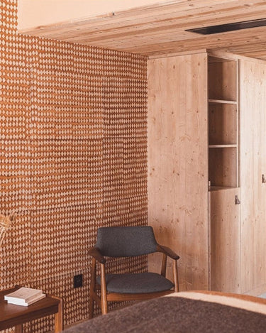 Papel pintado Diamond de papel de arroz en ocre y crudo · 4 m² de Le Monde Sauvage, aplicado en una habitación con sillón