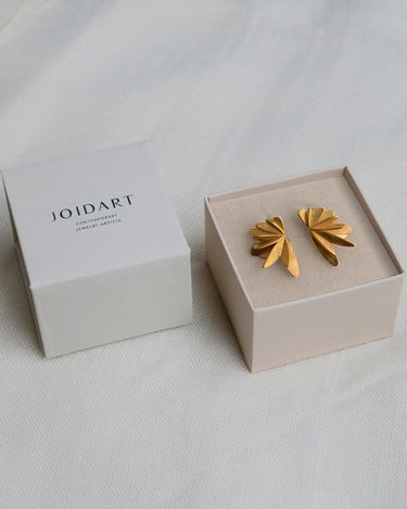 Dos pendientes dorados de elementos desplegados en caja clara con tapa Joidart.