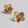 Par de pendientes dorados pequeños de flor de Joidart: dos pendientes dorados pequeños en forma de flor con pétalos estriados, sobre fondo claro.