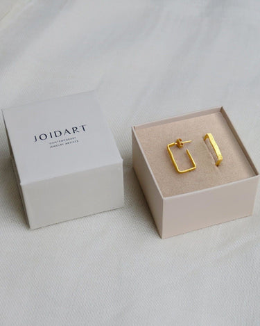 Par de aros rectangulares dorados estrechos en caja clara con tapa Joidart.