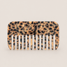 Peine de viaje de acetato con estampado de leopardo de Peignée Paris, sobre fondo topo claro.