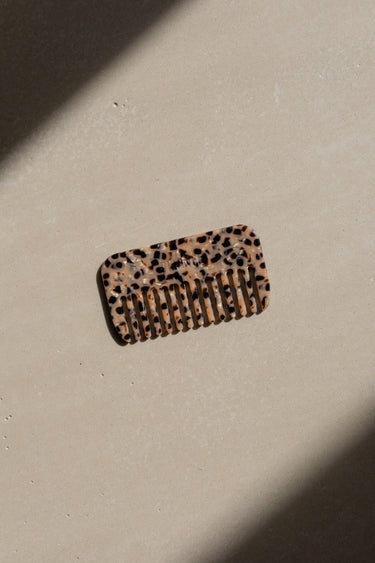 Peines de viaje de acetato con estampado de leopardo de Peignée Paris: una pieza sobre una superficie clara con luz natural.