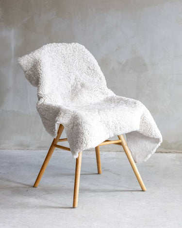 Piel de oveja Crossbreed blanca, colocada sobre un sillón
