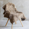 Piel de oveja Crossbreed marrón de pelo rizado, colocada sobre un sillón