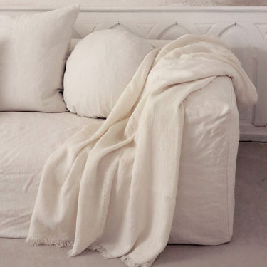 Plaid de lino blanco con flecos sobre un sofá blanco de Bed and Philosophy