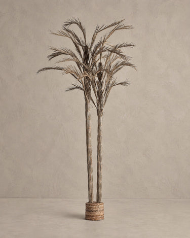 Planta artificial Vical de fibra natural en tonos neutros sobre pared y suelo topo claro texturizado
