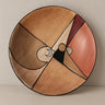 Plato decorativo con composición geométrica en tonos tierra y rojo, sobre fondo topo claro