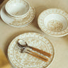Plato de postre de gres con arcos pintados en beige, en una mesa con cuencos y platos de Leandro Cano