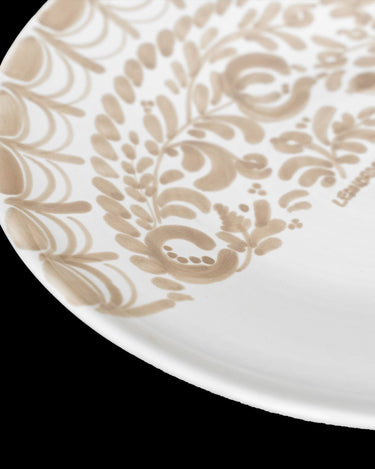 Decoración de platos de postre María Tudor: detalle de hojas y frutos beige sobre el esmalte blanco