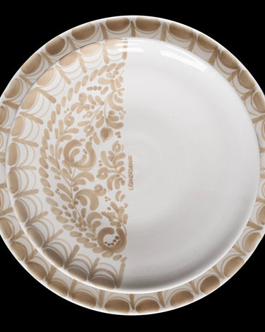 Plato María Tudor de dibujo lateral beige superpuesto sobre otro plato de la vajilla Leandro Cano