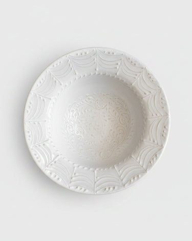 Plato hondo de gres blanco con relieves de arcos de Leandro Cano: plato hondo blanco desde arriba, con arcos en el borde y centro decorado.