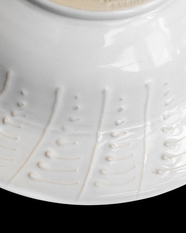 Plato hondo de gres blanco con relieves de hojas de Leandro Cano: detalle exterior del plato hondo blanco con trazos en relieve.