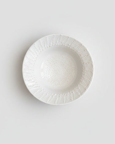 Plato de Leandro Cano: plato hondo blanco visto desde arriba, borde y centro decorados en relieve.